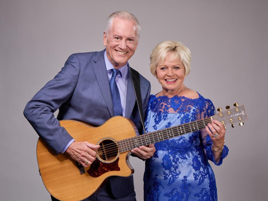 Et fotografi af Keld og Hilda Heick, der smiler mens Keld spiller på guitar